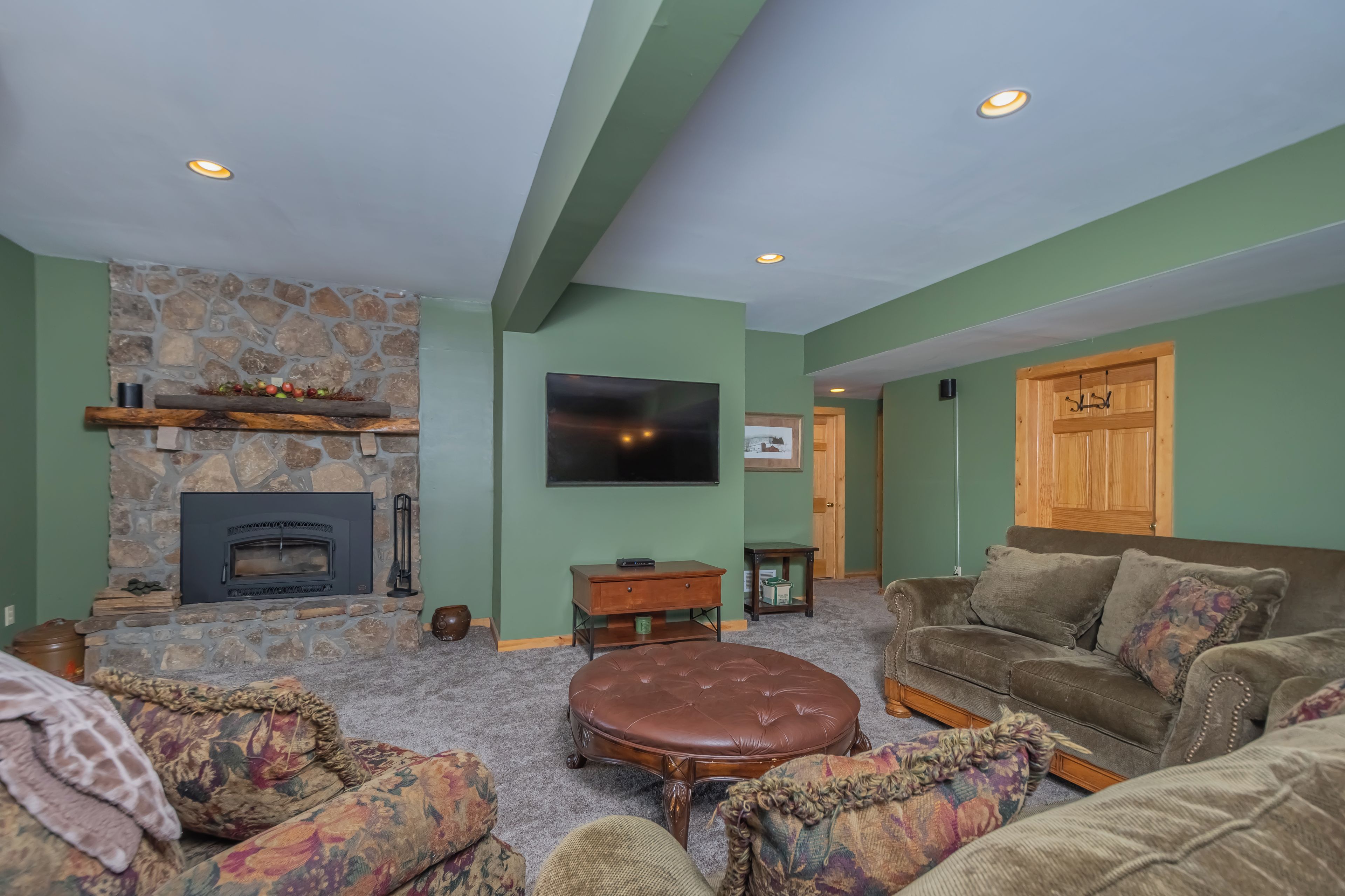 A cozy living room with a stone fireplace, a flat-screen TV, and comfortable seating.