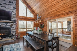 Cozy cabin interior with a large dining table, comfortable bench, and fireplace.