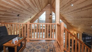A wooden interior with a high ceiling, a staircase, and a view through large windows. - Woods-stock by Taylor Made Deep Creek (McHenry)