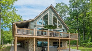 A two-story cabin with a balcony, stone foundation, and a hot tub. - Woods-stock by Taylor Made Deep Creek (McHenry)