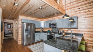 A modern kitchen with wooden walls, stainless steel appliances, and a granite countertop. - Woods-stock by Taylor Made Deep Creek (McHenry)
