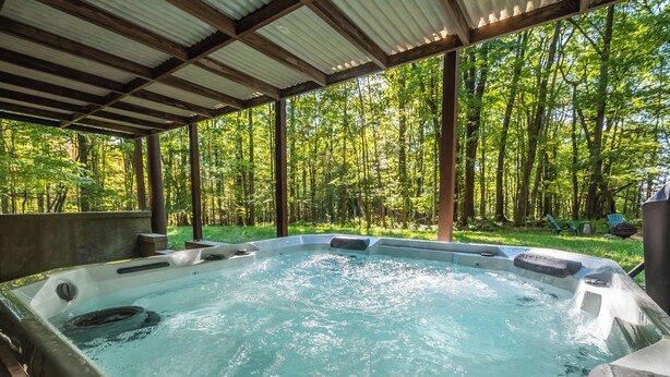 A hot tub with a wooden deck and a view of a forest. - Woodside Retreat by Taylor Made Deep Creek (McHenry)