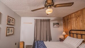 A bedroom with a bed, a nightstand, a ceiling fan, and a wooden headboard. - Woodside Retreat by Taylor Made Deep Creek (McHenry)