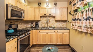 A kitchen with wooden cabinets, a stainless steel oven, a stove, and a coffee maker. - Woodside Retreat by Taylor Made Deep Creek (McHenry)