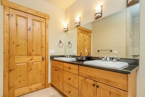 Ein Badezimmer mit Holzausstattung, einem großen Spiegel und zwei Waschbecken.