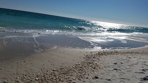 Une plage de galets et de sable, des vagues qui se rapprochent du rivage et un ciel dégagé.