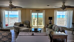 Un salon spacieux avec vue sur la plage, aménagé avec un canapé, un fauteuil et une table basse.