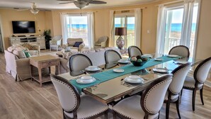Un coin repas avec une table en verre dressée pour six personnes, entourée de six chaises et agrémentée d’un chemin de table turquoise.