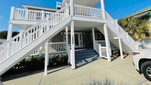 A two-story building with a covered porch and a staircase leading to the entrance. - Spacious Beach Duplex | 5 Bedrooms | Pool  #B (North Myrtle Beach)