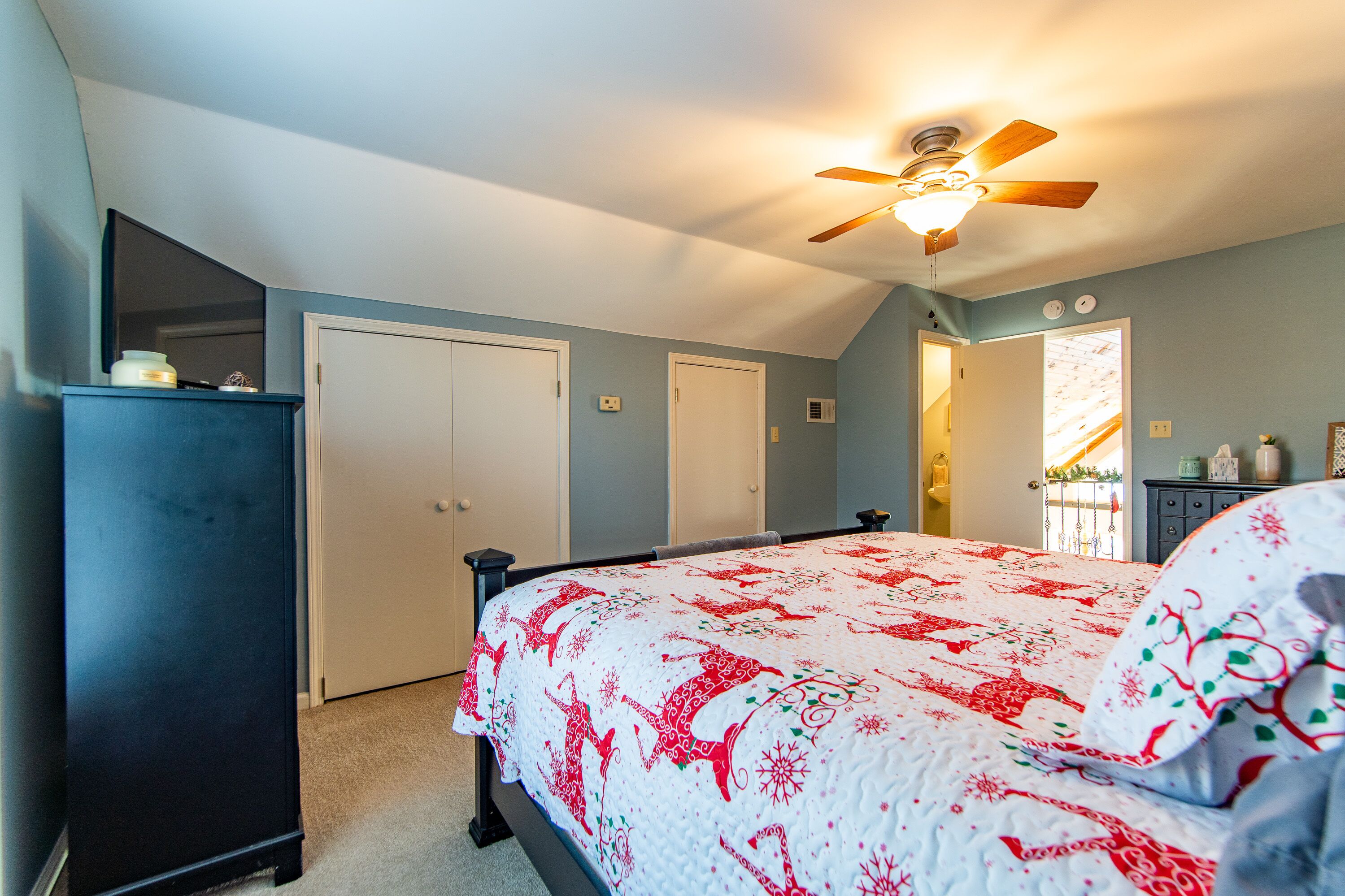 A bedroom with a bed, a ceiling fan, and a wardrobe.
