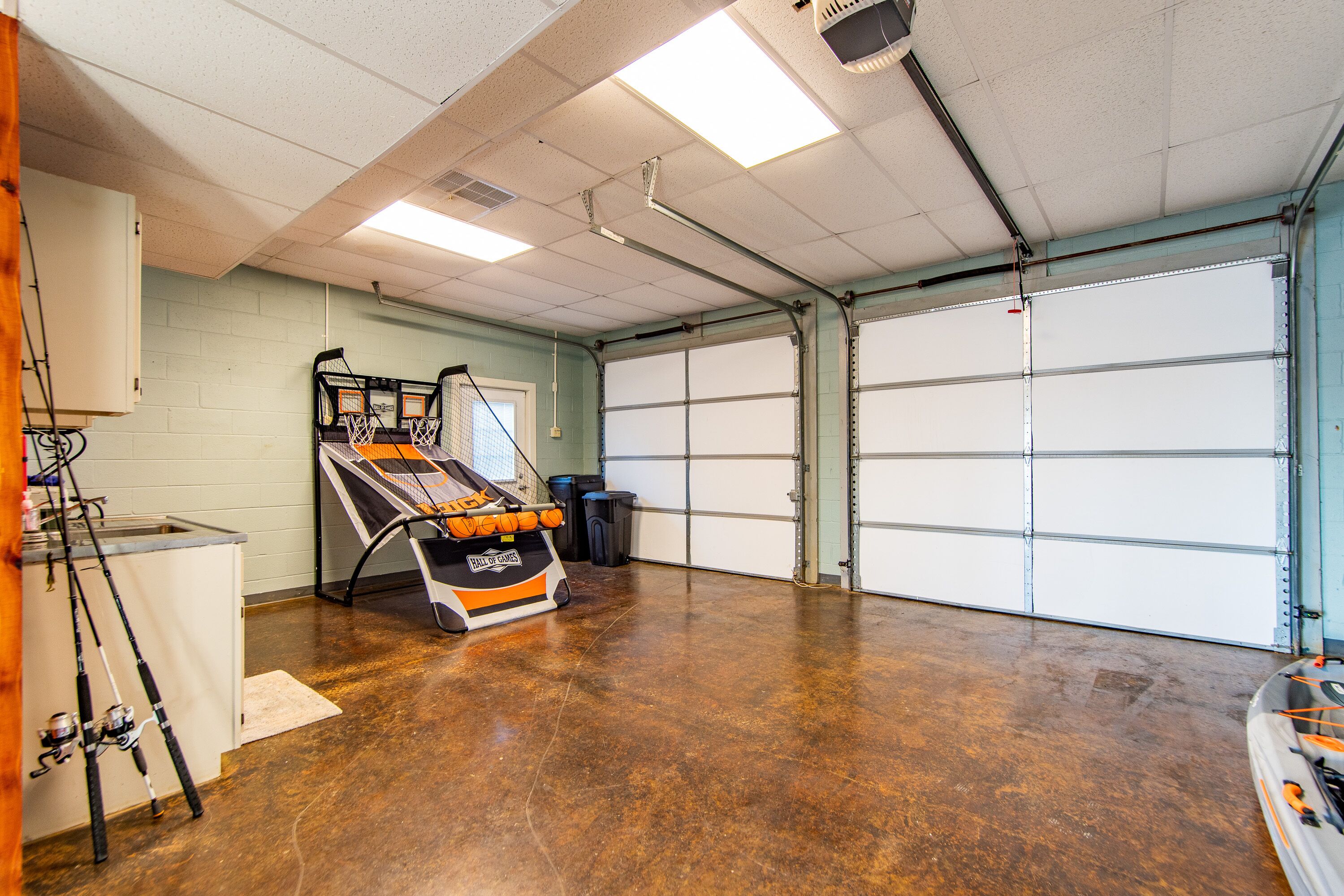 Een ruime garage met een betonnen vloer, een vismachine en een gesloten garagedeur.