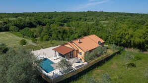 A house with a swimming pool, a covered patio, and a view of a forested area. - 3 BD Villa with Private pool, Jacuzzi and Volleyball Court (Umag)