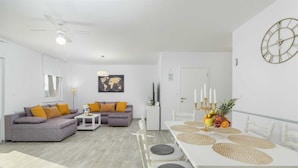 A modern living room with a grey sofa, a white coffee table, and a dining table with placemats. - 3 BD Villa with Private pool, Jacuzzi and Volleyball Court (Umag)