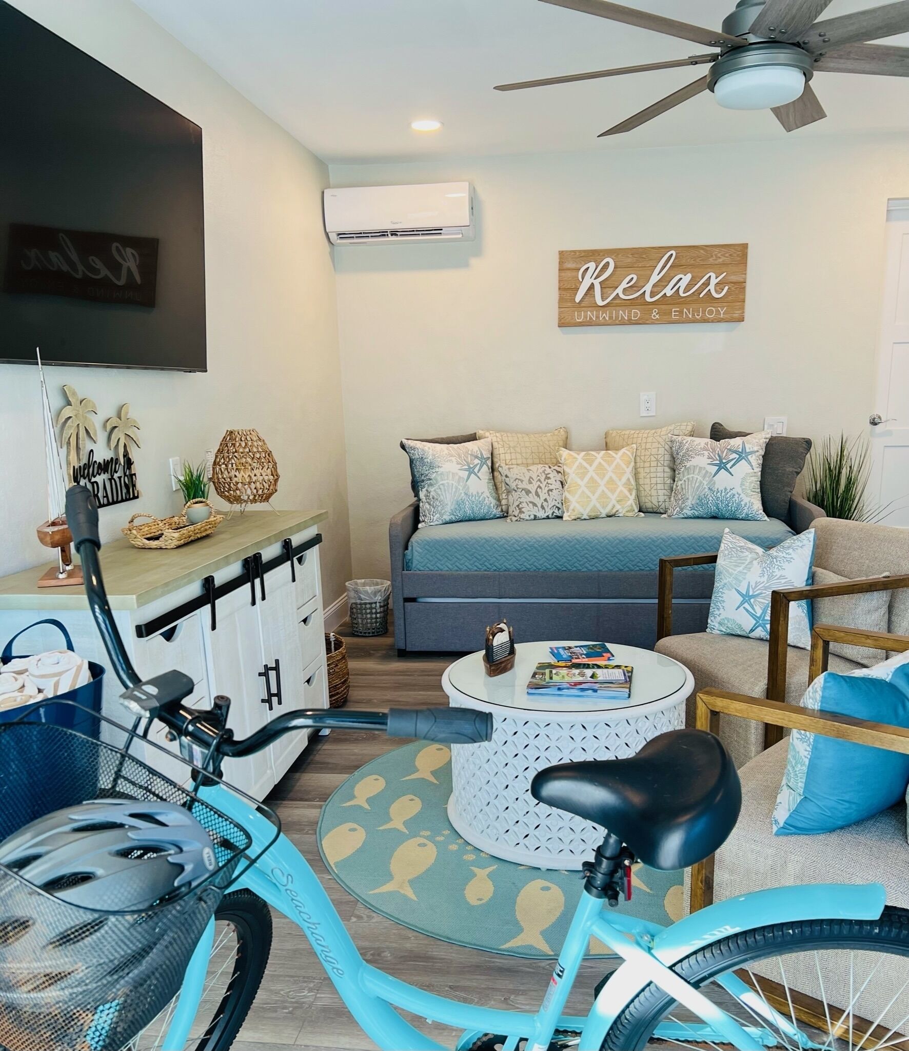 A living room with a sofa, a coffee table, a bicycle, and a ceiling fan.