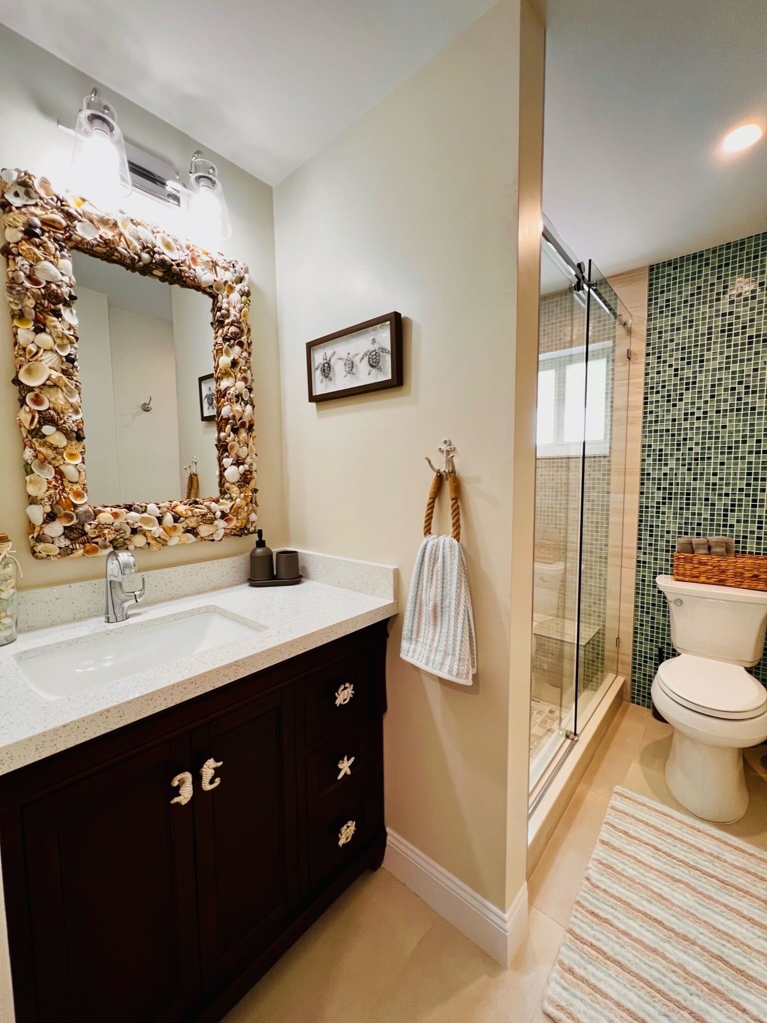 A bathroom with a large mirror, dark wooden vanity, white sink, and a glass shower enclosure.