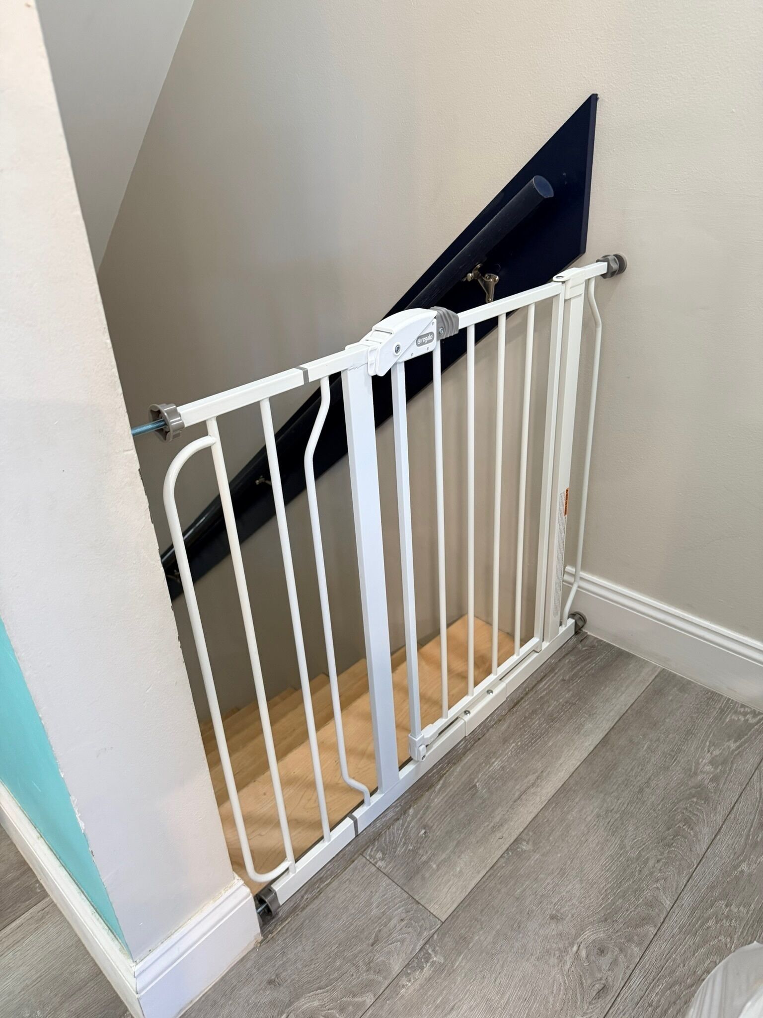 Een wit poortje voor baby's is geplaatst bovenaan een trap.