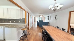 Una cocina amplia con armarios blancos, encimera de granito y mesa de comedor de madera con taburetes de bar.