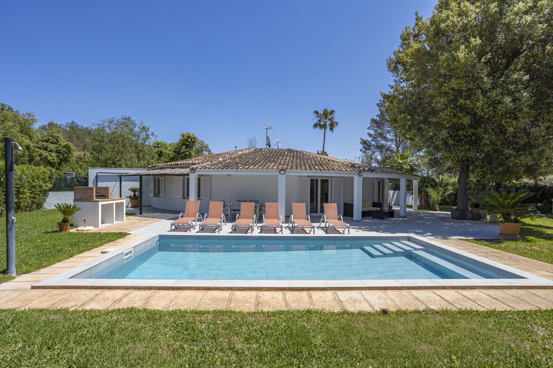 Une maison moderne dotée d’une piscine, d’un espace salon extérieur et d’un jardin.