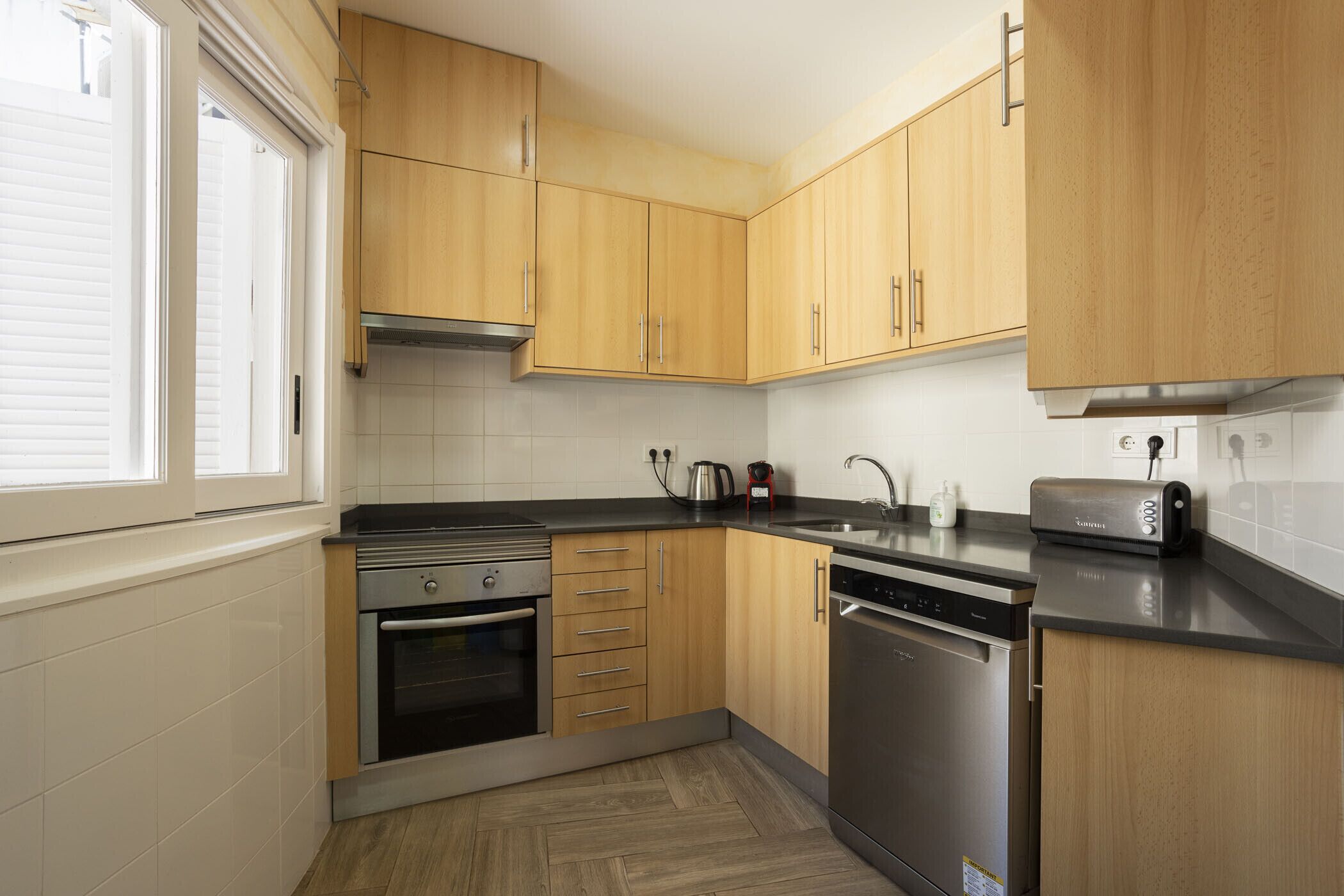Una cocina moderna con armarios de madera, electrodomésticos de acero inoxidable y encimera negra.