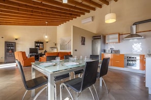 A modern kitchen with a dining area, featuring a wooden ceiling, built-in appliances, and orange cabinetry. - Villa with 3 bedrooms and 2 bathrooms, with pool and barbecue (Buger)