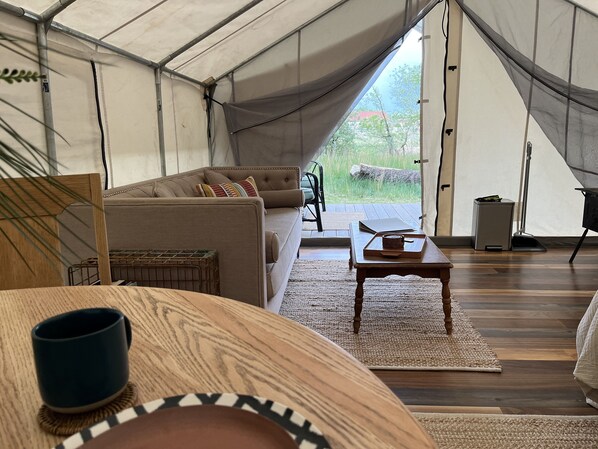 Une pièce aménagée comme une tente, avec un canapé, une table basse et une vue sur l’extérieur.