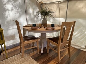 Une table ronde en bois, avec deux chaises, un vase de fleurs et deux tasses posées sur la table.