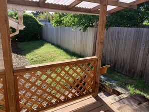 Enjoy the serene view from this elevated deck overlooking a lush backyard with a tree and grassy area.