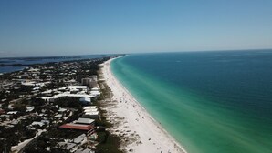An aerial view of a coastal town with a long sandy beach and a clear blue ocean. - Summer House-8 bedroom, Rooftop, short walk to the beach, private pool/spa and w (Holmes Beach)
