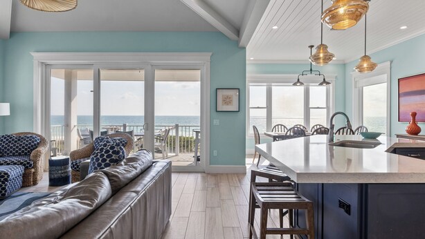 A spacious living area with a view of the ocean, a large seating area, and a kitchen with a central island.