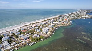 An aerial view of a coastal town with residential buildings, a beach, and a marina.