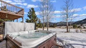 A hot tub in a snowy outdoor setting with a wooden deck and a view of mountains. - Lily Mountain Lodge - Amazing Mountains Views, Private Hot Tub, Great Location (Estes Park)