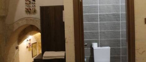 A bathroom with a tiled shower, a wooden bench, and a dark wooden cabinet.