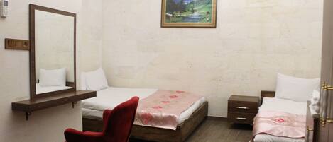 A bedroom with two beds, a red chair, a wooden nightstand, a bedside table, a mirror, and a framed picture on the wall.