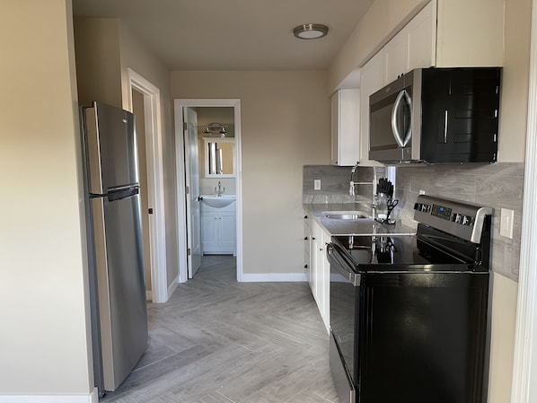 A modern kitchen with a refrigerator, stove, microwave, and sink.