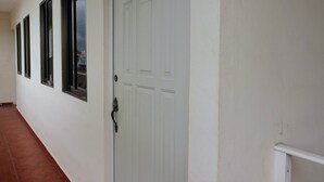 A hallway with white walls, a white door, and a window with a black frame. - San Román room inside the historic center (Campeche)