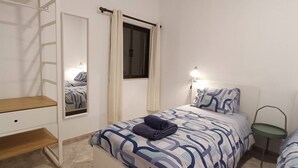 Une chambre à coucher avec un lit, une table de chevet, une lampe et un miroir.