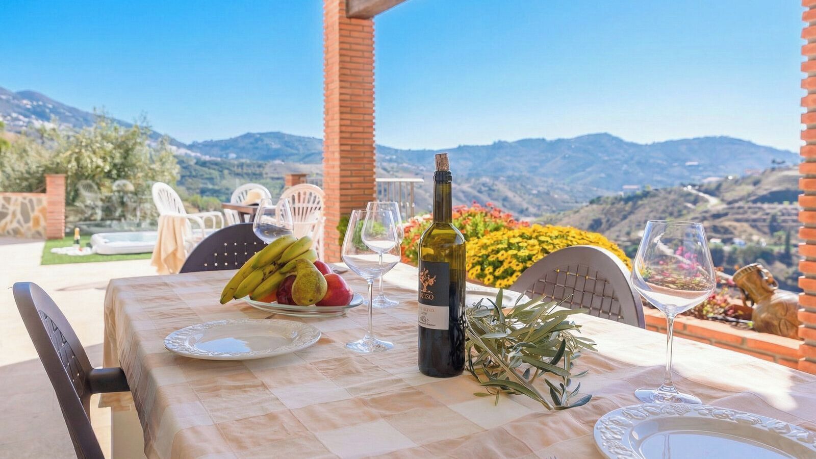 A table set for dining with a bottle of wine, plates, and a fruit bowl.