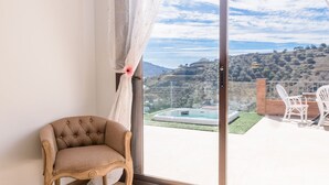 A balcony with a chair, a pool, and a view of a hilly landscape. - El Refugio de Árchez by Ruralidays (Málaga)