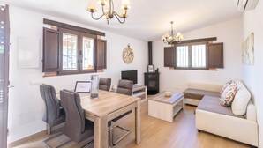 A modern living room with a wooden dining table, two sofas, a TV, and a fireplace. - El Refugio de Árchez by Ruralidays (Málaga)