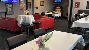Un salón de conferencias con mesas, sillas y una pantalla de televisión.