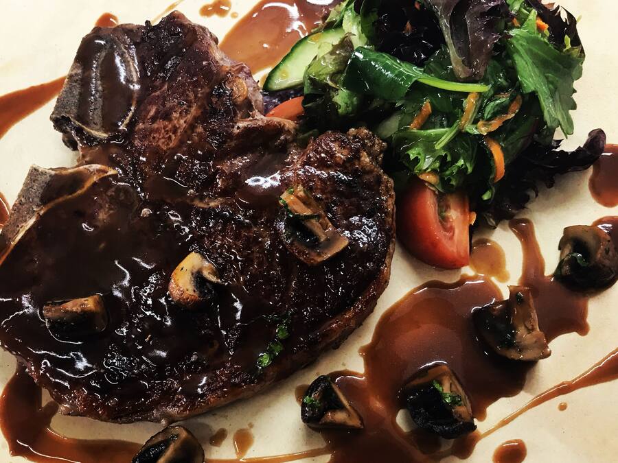 A plate with a steak, mushrooms, and a salad.