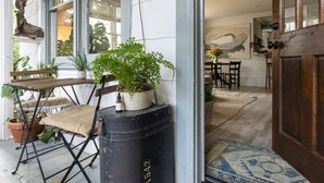 Een rustiek interieur met een houten deur, een kamerbreed tapijt met dessin en een tafel met plantenpotten.