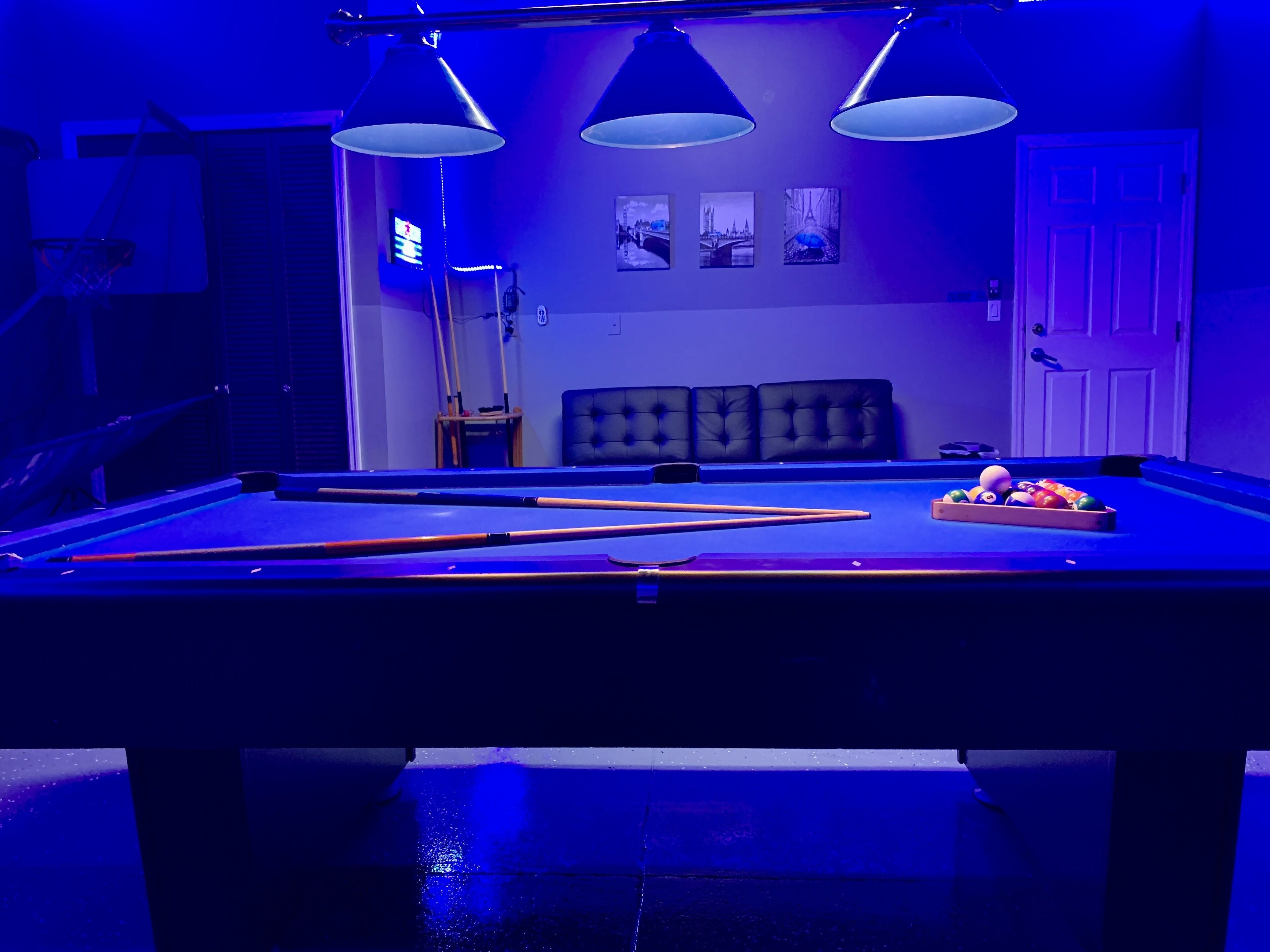 A pool table with three overhead lamps, a pool cue rack, and a fruit bowl.
