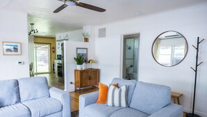Ein Wohnzimmer mit zwei grauen Sofas, einem Holztisch, einem Spiegel und einer Holzkommode.