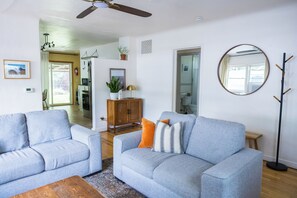 A living room with two grey sofas, a wooden coffee table, a mirror, and a wooden cabinet.