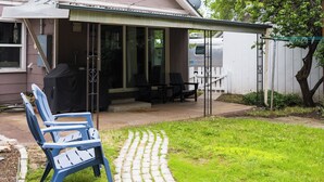 Ein Haus mit überdachter Veranda, einem Rasen und einem gepflasterten Weg, der zum Eingang führt.