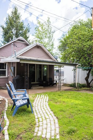 A house with a covered porch, a lawn, and a paved pathway leading to the entrance.