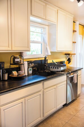 A kitchen with white cabinetry, a black countertop, and stainless steel appliances.