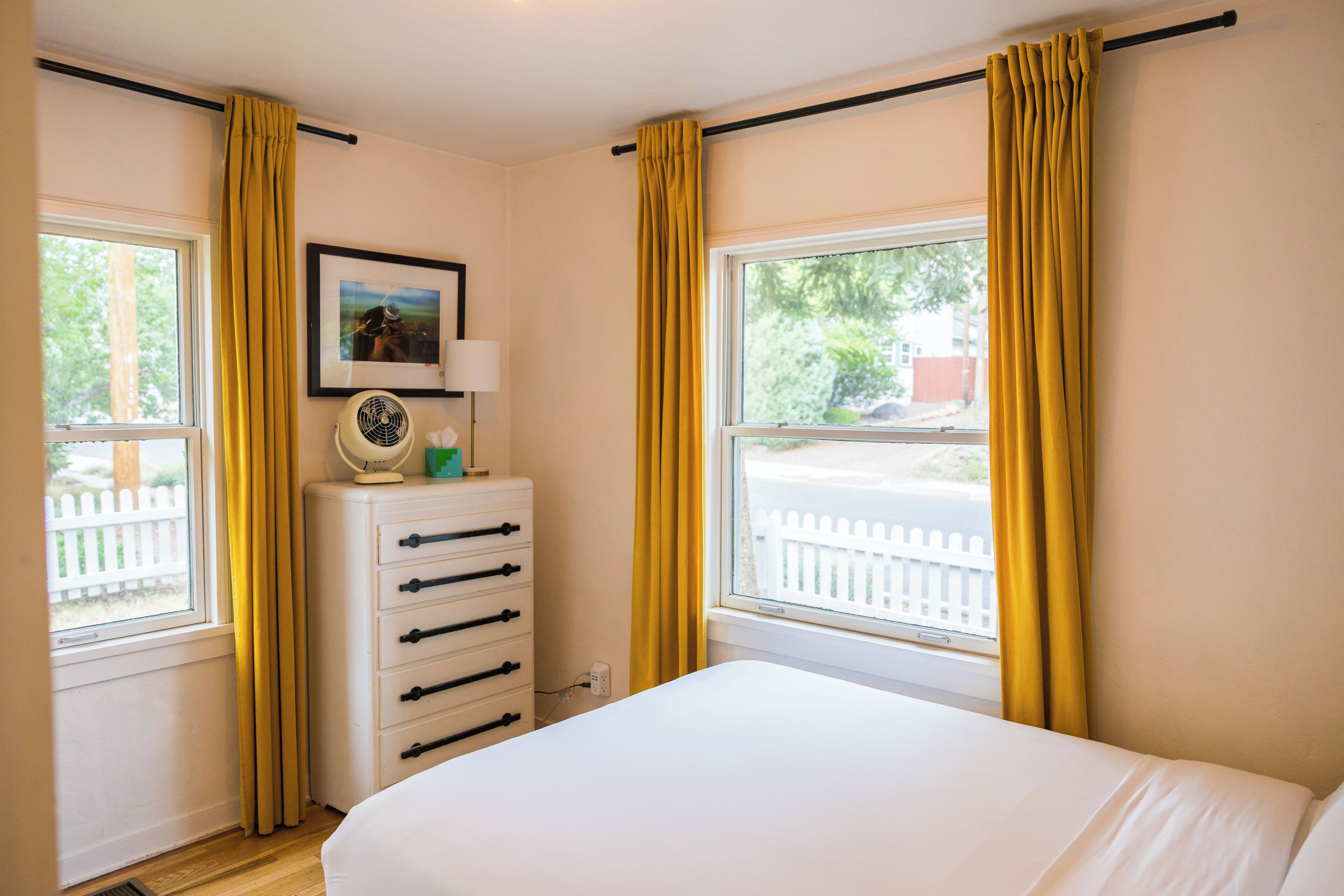 A bedroom with a bed, a dresser, a lamp, and a picture on the wall.