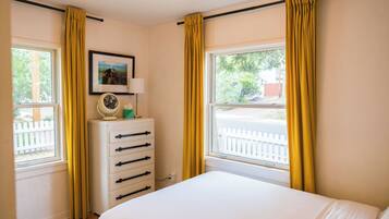 A bedroom with a bed, a dresser, a lamp, and a picture on the wall.